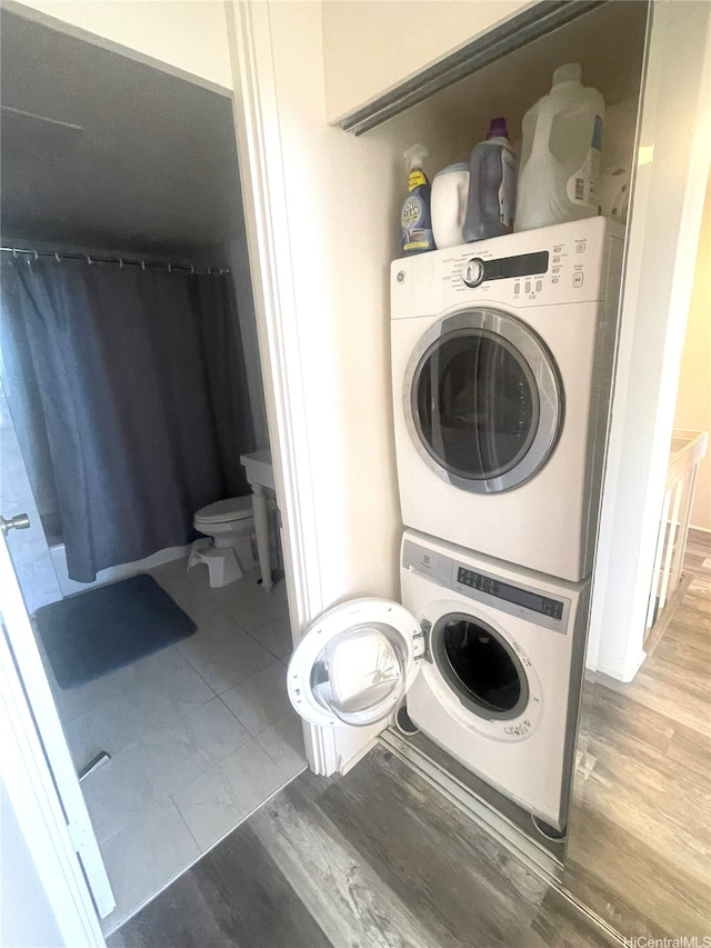 laundry room featuring laundry area, wood finished floors, and stacked washer / dryer