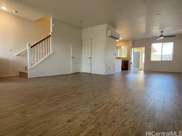 91-960 Iwikuamoo St Unit 304, Ewa Beach, HI 96706 - unfurnished living room with stairs, an AC wall unit, ceiling fan, and wood finished floors