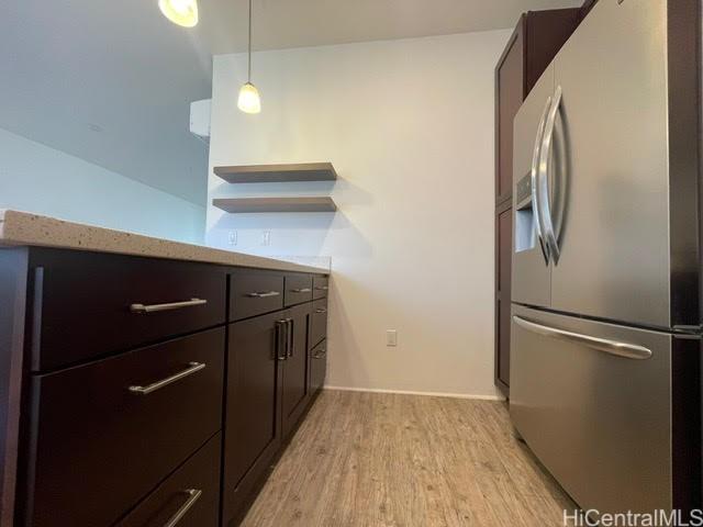 91-960 Iwikuamoo St Unit 304, Ewa Beach, HI 96706 - kitchen featuring dark brown cabinetry, open shelves, stainless steel fridge, light wood finished floors, and light countertops