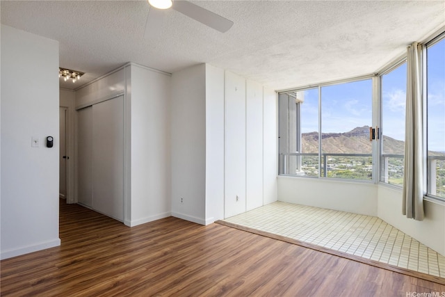2600 Pualani Way Unit 3102, Honolulu, HI 96815 - empty room with a textured ceiling, a ceiling fan, wood finished floors, a mountain view, and baseboards