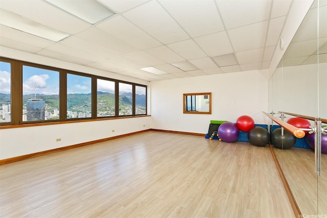 exercise room with light wood-style floors, a drop ceiling, and baseboards