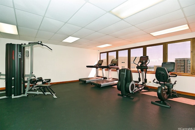exercise room featuring baseboards and a paneled ceiling