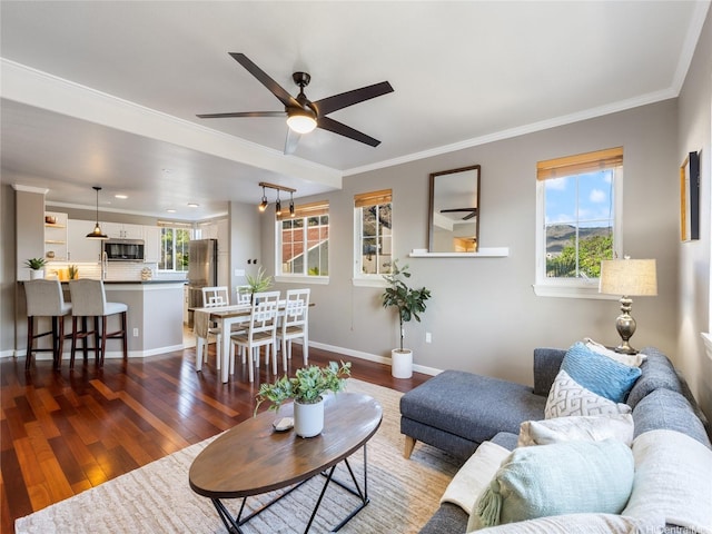 living room featuring dark wood-type flooring, crown molding, baseboards, and ceiling fan