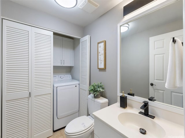 half bath with vanity, toilet, washer / dryer, visible vents, and a closet