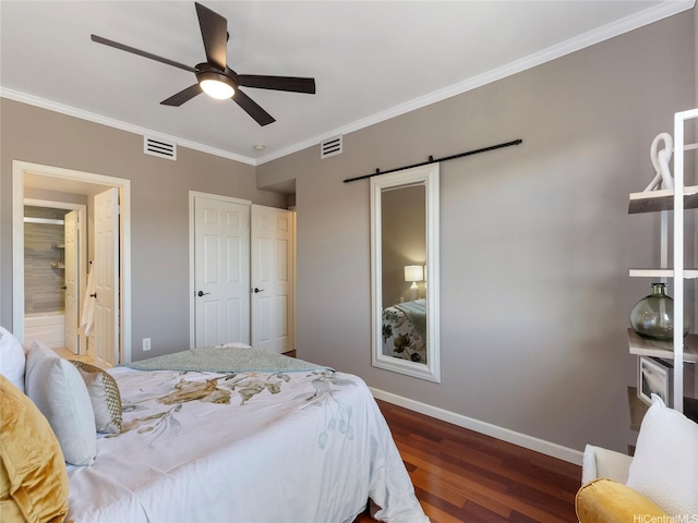 bedroom featuring a barn door, baseboards, wood finished floors, visible vents, and ornamental molding