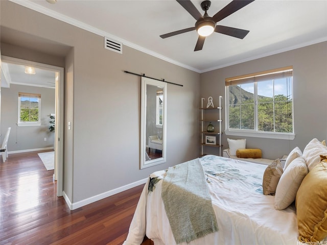 bedroom featuring visible vents, crown molding, a barn door, baseboards, and dark wood-type flooring