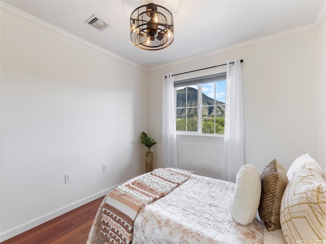 bedroom featuring a notable chandelier, baseboards, wood finished floors, visible vents, and ornamental molding