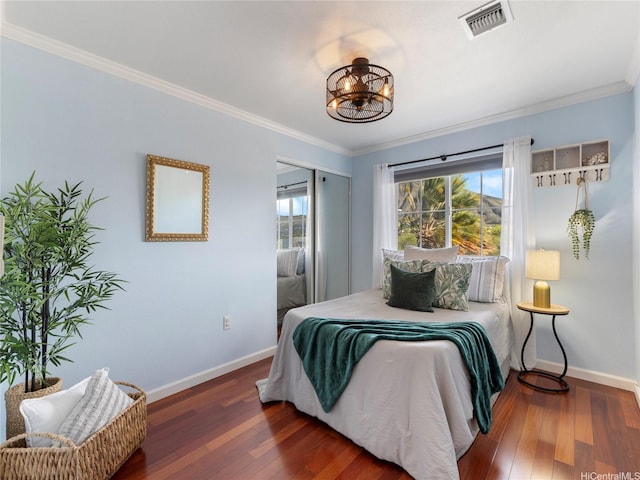bedroom with baseboards, visible vents, wood finished floors, and a closet