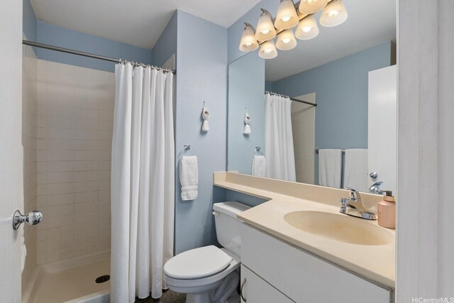 bathroom featuring vanity, a tile shower, and toilet