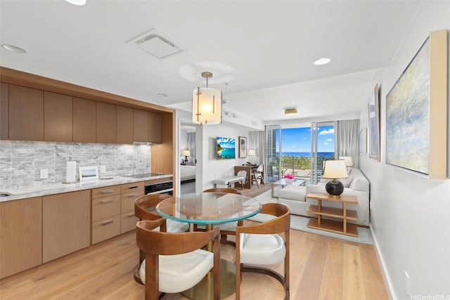 kitchen with light wood-style floors, light countertops, backsplash, and visible vents
