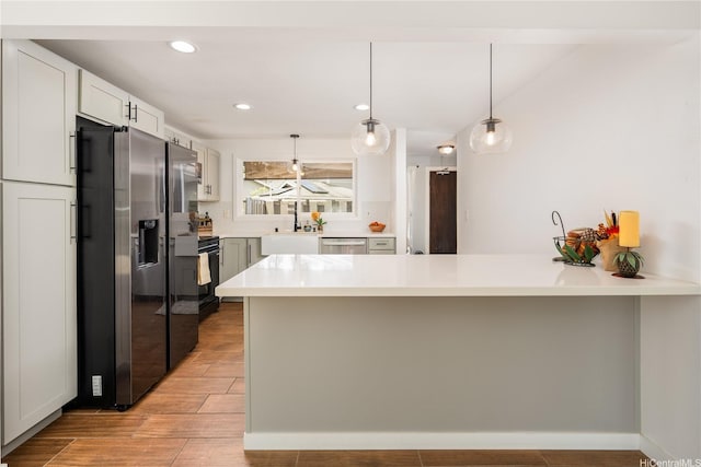 94-1081 Anania Cir Unit 12, Mililani, HI 96789 - kitchen with a peninsula, light countertops, a sink, appliances with stainless steel finishes, and hanging light fixtures