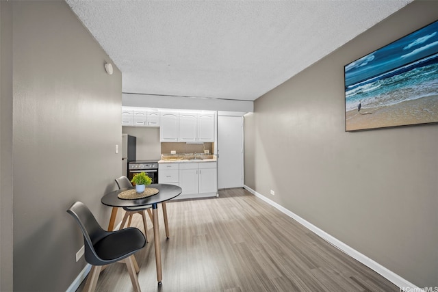 1459 Pele St Unit 206, Honolulu, HI 96813 - interior space with oven, a textured ceiling, light wood-style flooring, white cabinetry, and baseboards