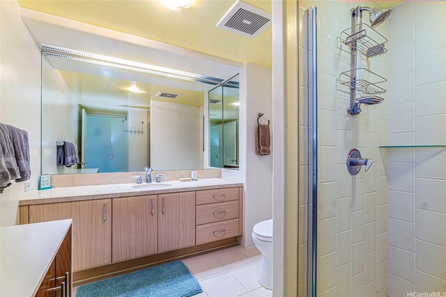 bathroom with vanity, tile patterned flooring, a tile shower, and toilet