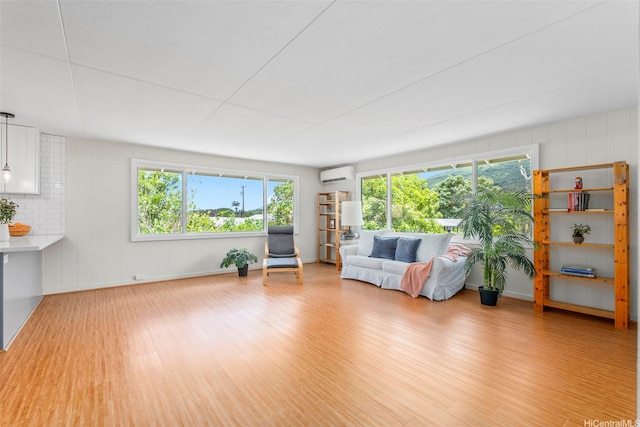 living area featuring wood finished floors, an AC wall unit, and baseboards