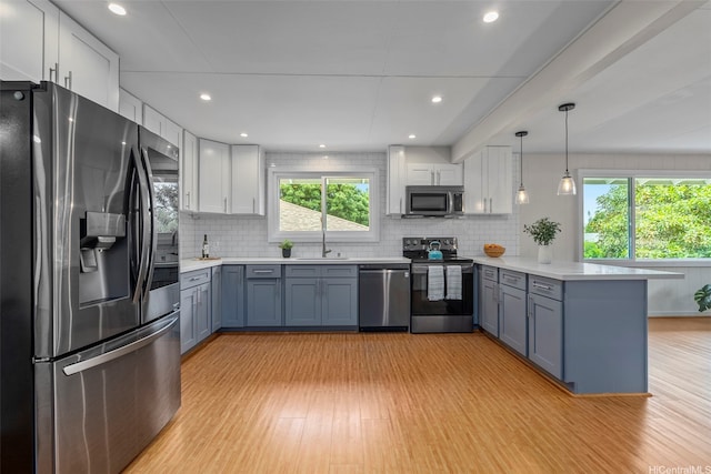 kitchen with stainless steel appliances, a peninsula, a sink, light countertops, and recessed lighting
