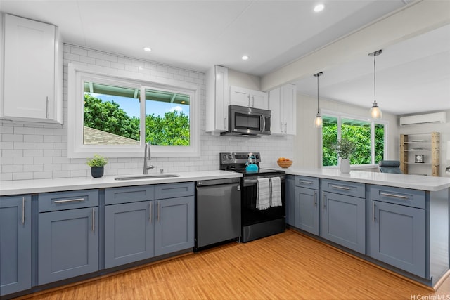 kitchen featuring appliances with stainless steel finishes, a sink, a peninsula, white cabinetry, and recessed lighting