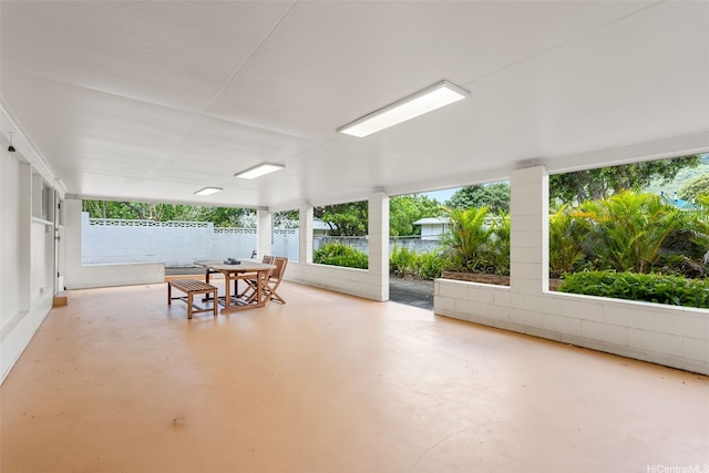 sunroom featuring outdoor dining area, concrete floors, and plenty of natural light