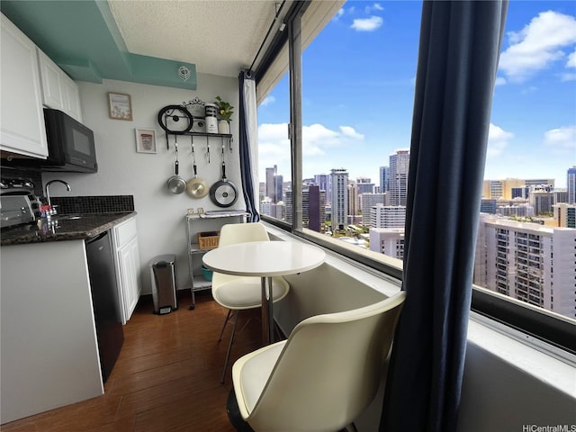 interior space with white cabinets, black microwave, dishwasher, dark wood finished floors, and a city view