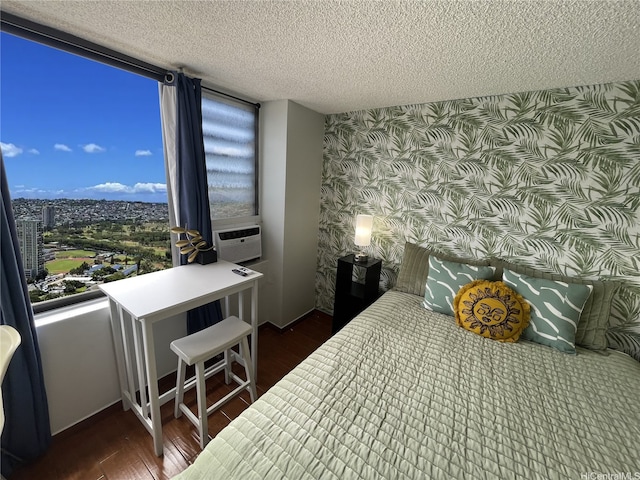 bedroom featuring an accent wall, wallpapered walls, a textured ceiling, cooling unit, and dark wood finished floors