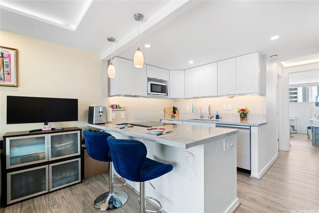 2611 Ala Wai Blvd Unit 1805, Honolulu, HI 96815 - kitchen with appliances with stainless steel finishes, light wood-style floors, a breakfast bar, white cabinetry, and recessed lighting
