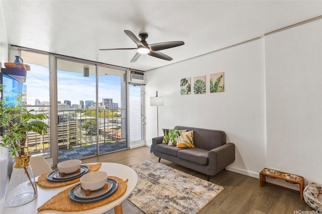 living area with a ceiling fan, a wall mounted AC, wood finished floors, baseboards, and a city view