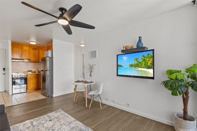 living area featuring baseboards, light wood-style flooring, and ceiling fan