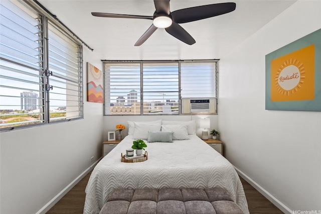 bedroom with a ceiling fan, baseboards, wood finished floors, and cooling unit