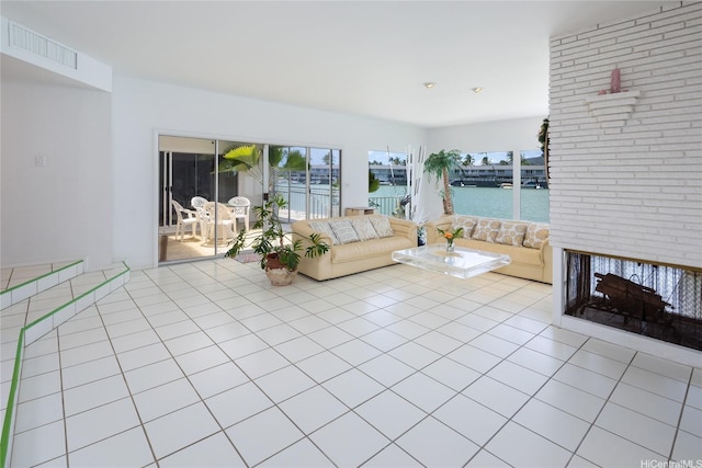 living room featuring light tile patterned floors, a water view, visible vents, and plenty of natural light