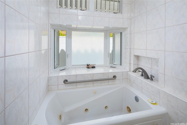 bathroom with a tub with jets and tile walls