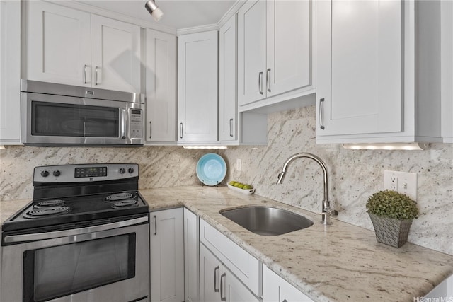 kitchen featuring a sink, stainless steel appliances, backsplash, white cabinets, and light stone countertops