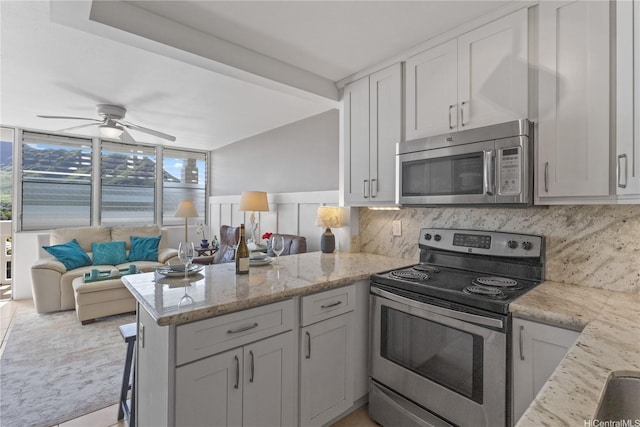 kitchen featuring backsplash, a peninsula, appliances with stainless steel finishes, and a ceiling fan