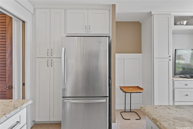 kitchen featuring freestanding refrigerator, white cabinetry, and light tile patterned flooring