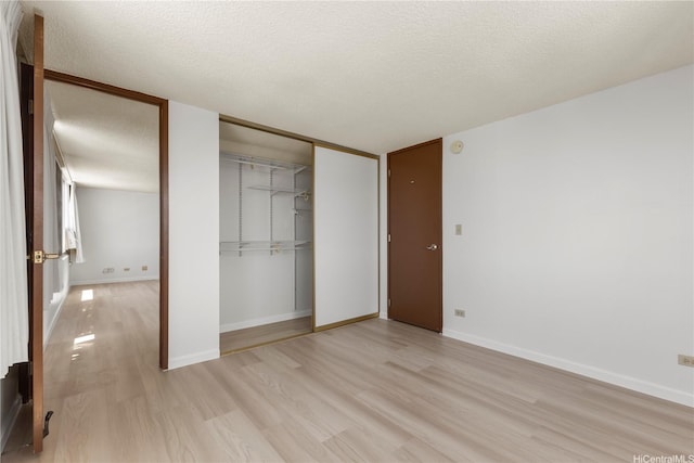 unfurnished bedroom with baseboards, a textured ceiling, light wood-style flooring, and a closet