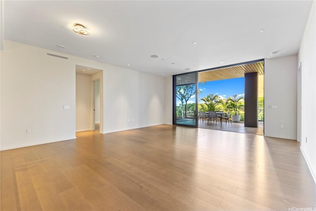 unfurnished room with visible vents, baseboards, floor to ceiling windows, and wood finished floors