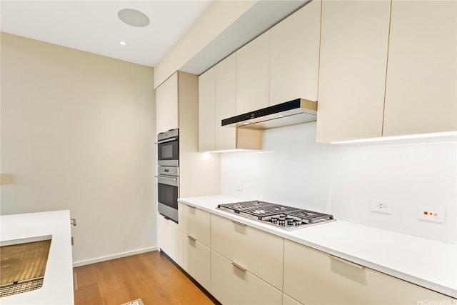 kitchen with light countertops, appliances with stainless steel finishes, cream cabinets, and under cabinet range hood