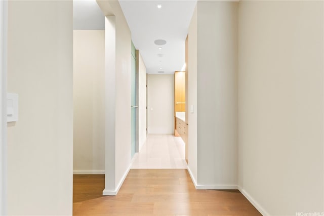 corridor with baseboards and light wood-style flooring