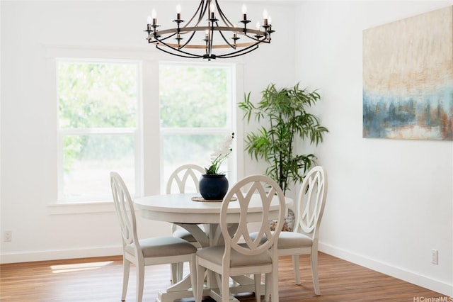 dining space with baseboards, a notable chandelier, a healthy amount of sunlight, and wood finished floors