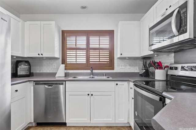 kitchen with a sink, backsplash, stainless steel appliances, and white cabinetry