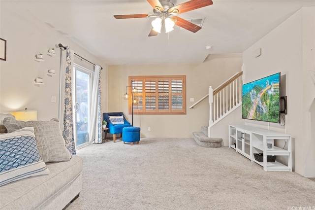 carpeted living area with a ceiling fan, visible vents, and stairway