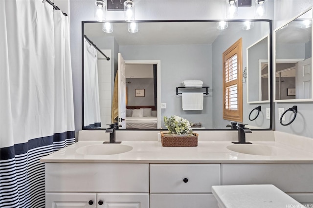 ensuite bathroom with connected bathroom, double vanity, and a sink