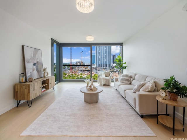 living room with a wall of windows, a view of city, an inviting chandelier, and light wood-style flooring