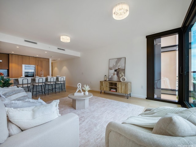 living area featuring baseboards, light wood-style floors, and visible vents