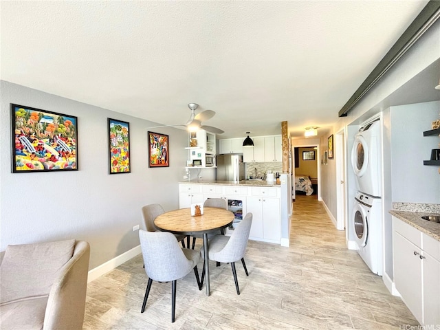 dining area with baseboards, stacked washer and clothes dryer, and ceiling fan