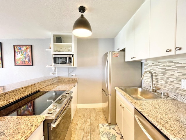 kitchen featuring open shelves, decorative backsplash, a sink, light wood finished floors, and stainless steel appliances