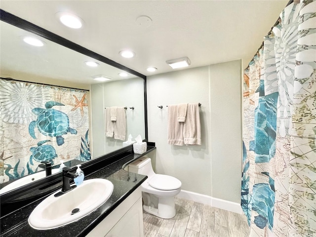 bathroom with vanity, wood finished floors, toilet, baseboards, and recessed lighting