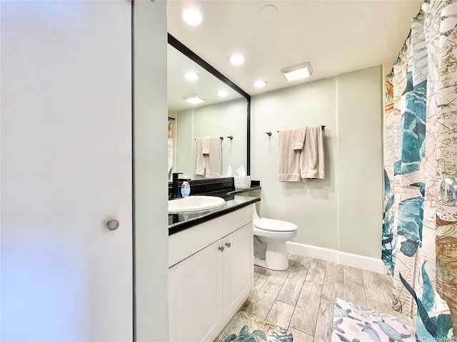 bathroom featuring vanity, toilet, recessed lighting, baseboards, and wood finished floors