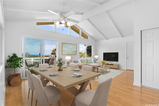 dining space with high vaulted ceiling, ceiling fan, beamed ceiling, and light wood-type flooring