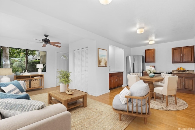 living area featuring baseboards, ceiling fan, and light wood-style flooring