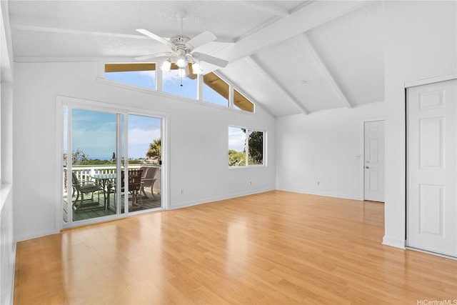 spare room featuring baseboards, ceiling fan, light wood finished floors, and beam ceiling