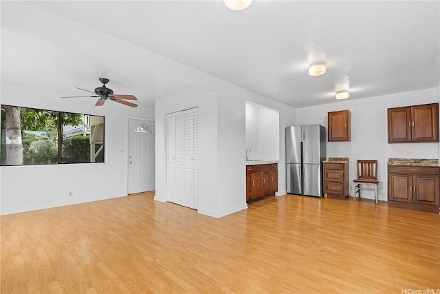 unfurnished living room featuring baseboards, a ceiling fan, and light wood-style flooring